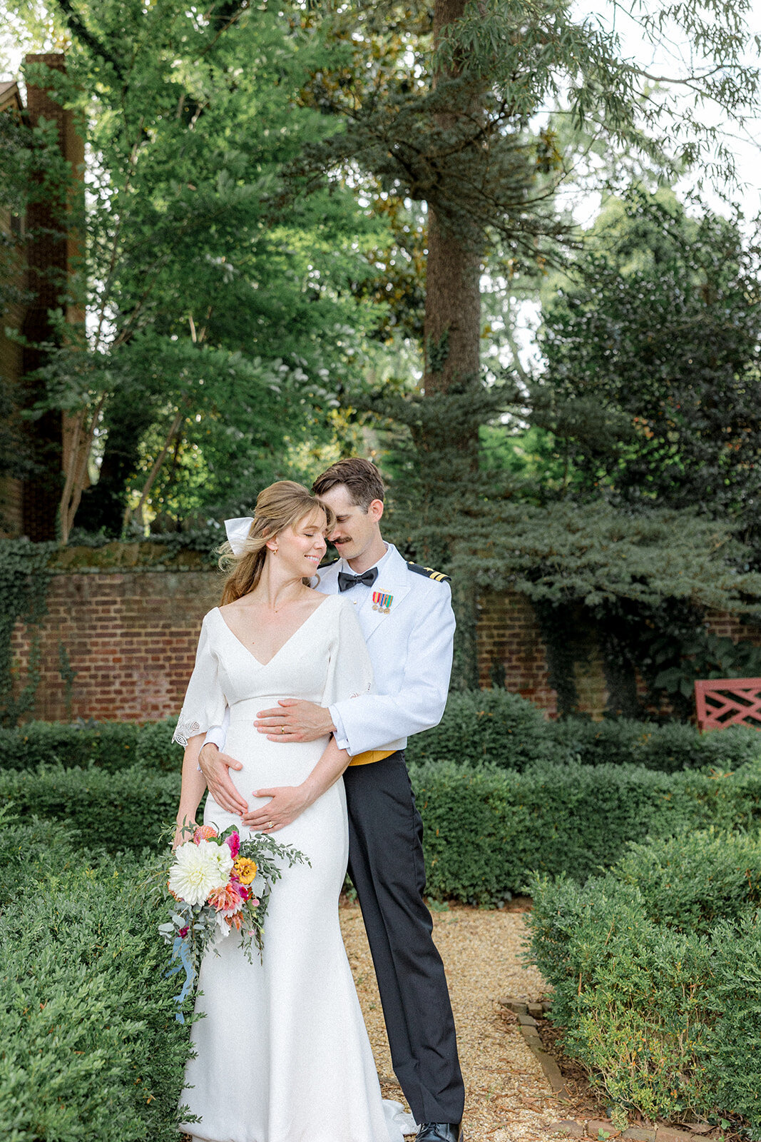 Groom holding pregnant wife's stomach