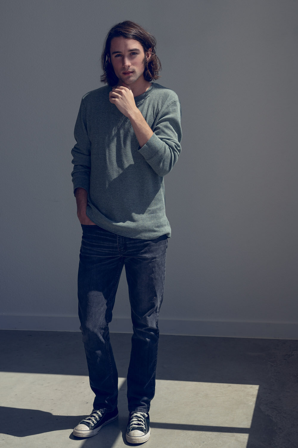 Editorial portrait of a man indoors, softly lit by window light with a faded, cinematic look.