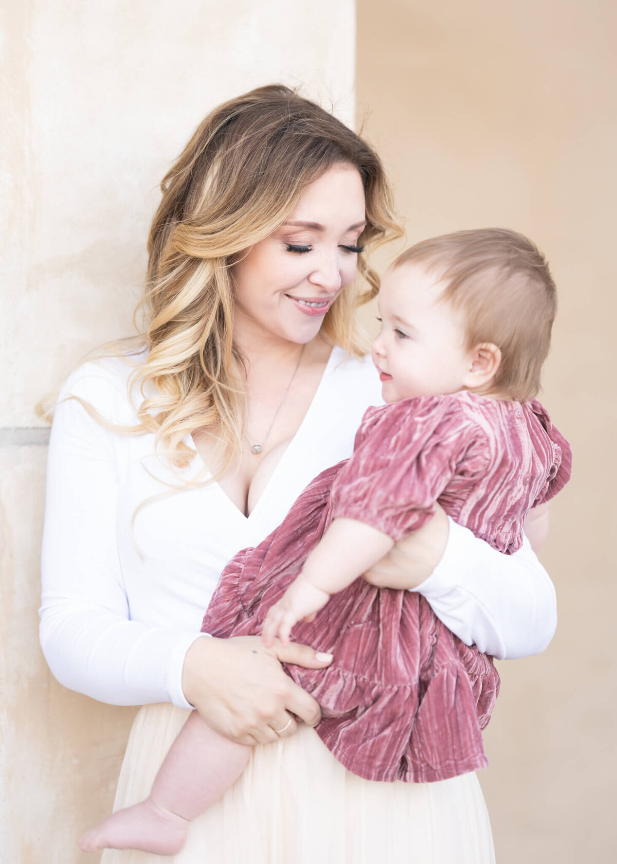 Mother in white holding baby in pink velvet