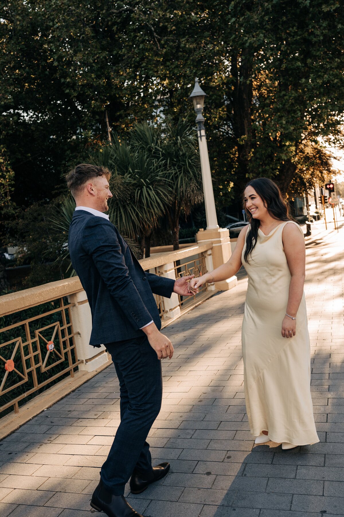 couple in pale yellow satin dress and blue suit in christchurch cbd for their engagement shoot