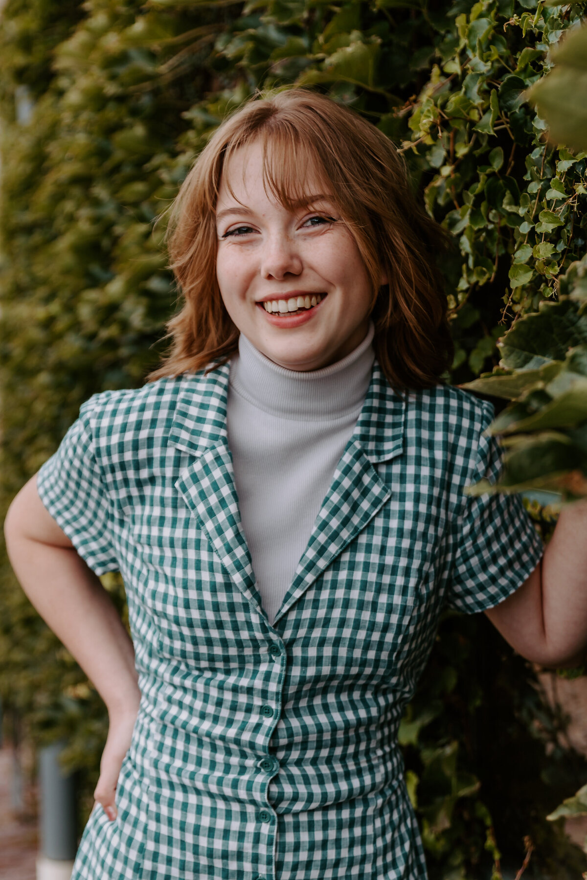 A young girl leaning on vines and smiling