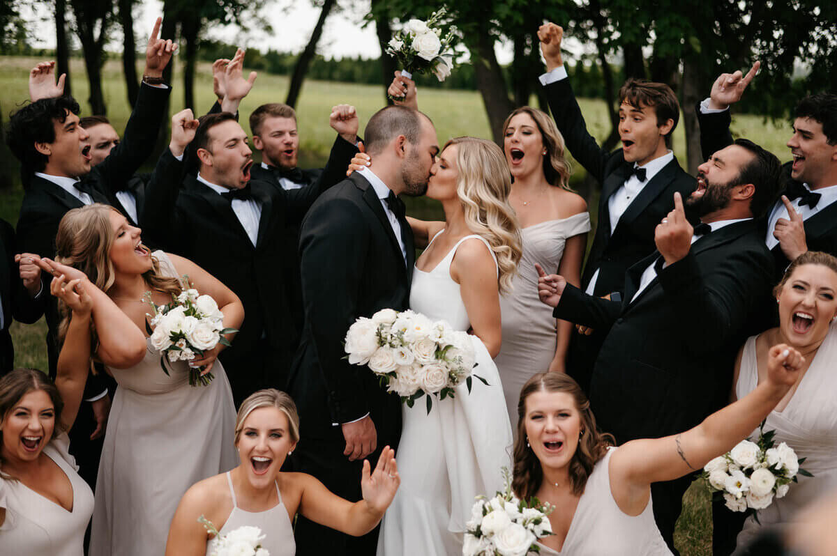 Bride and groom kissing surrounded by bridal party to show planning a wedding in chicago