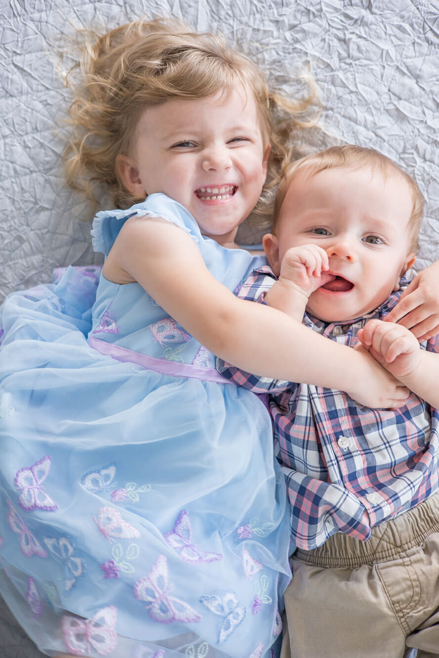 a toddler girl hugging a baby boy