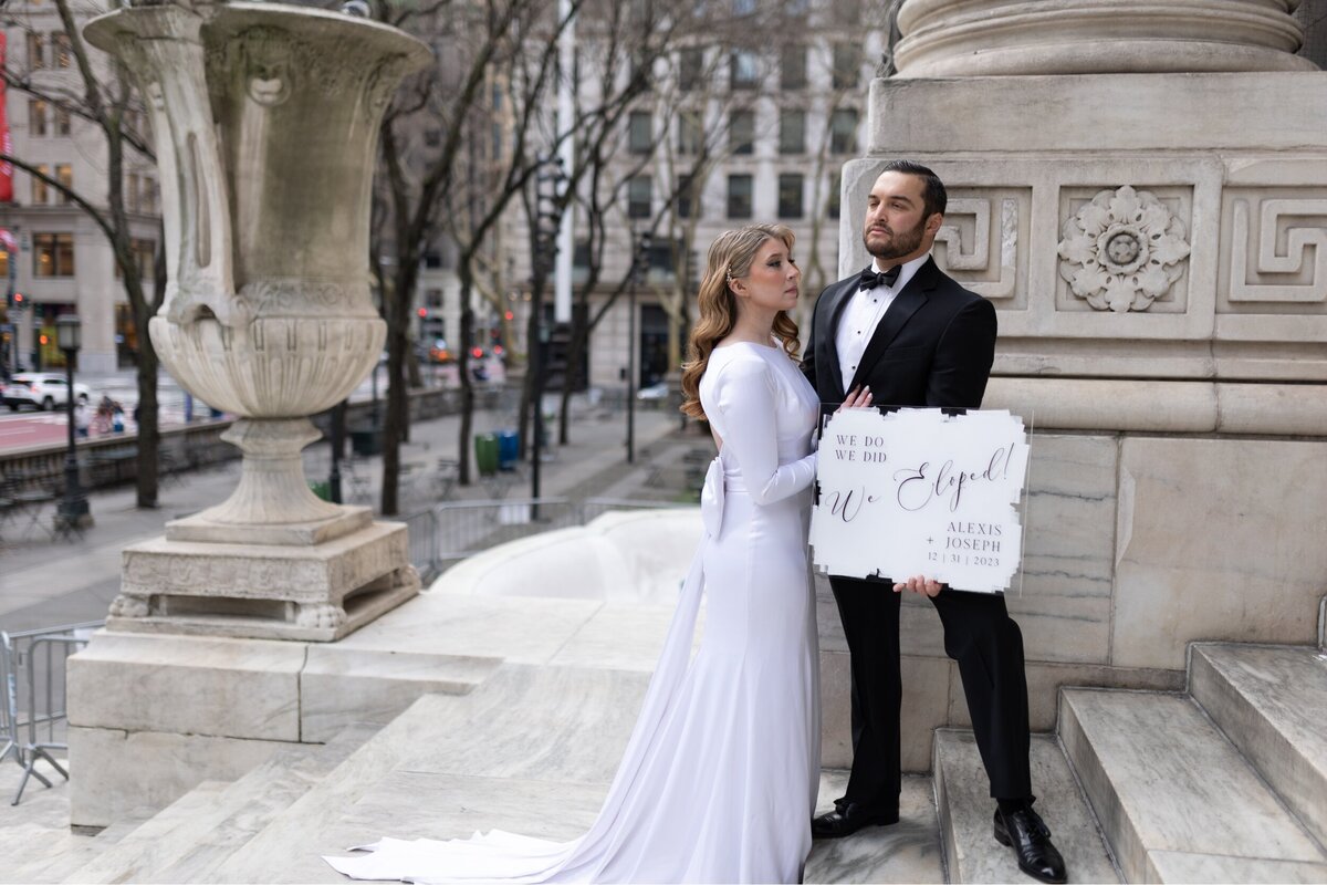 Bride and Groom holding a 'we eloped' sign right after saying their vows in NYC