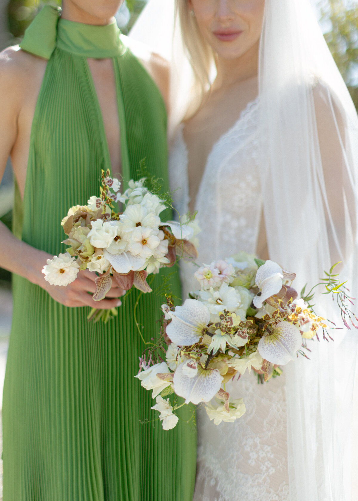 bridesmaid wearing green dress next to bride with bouquets