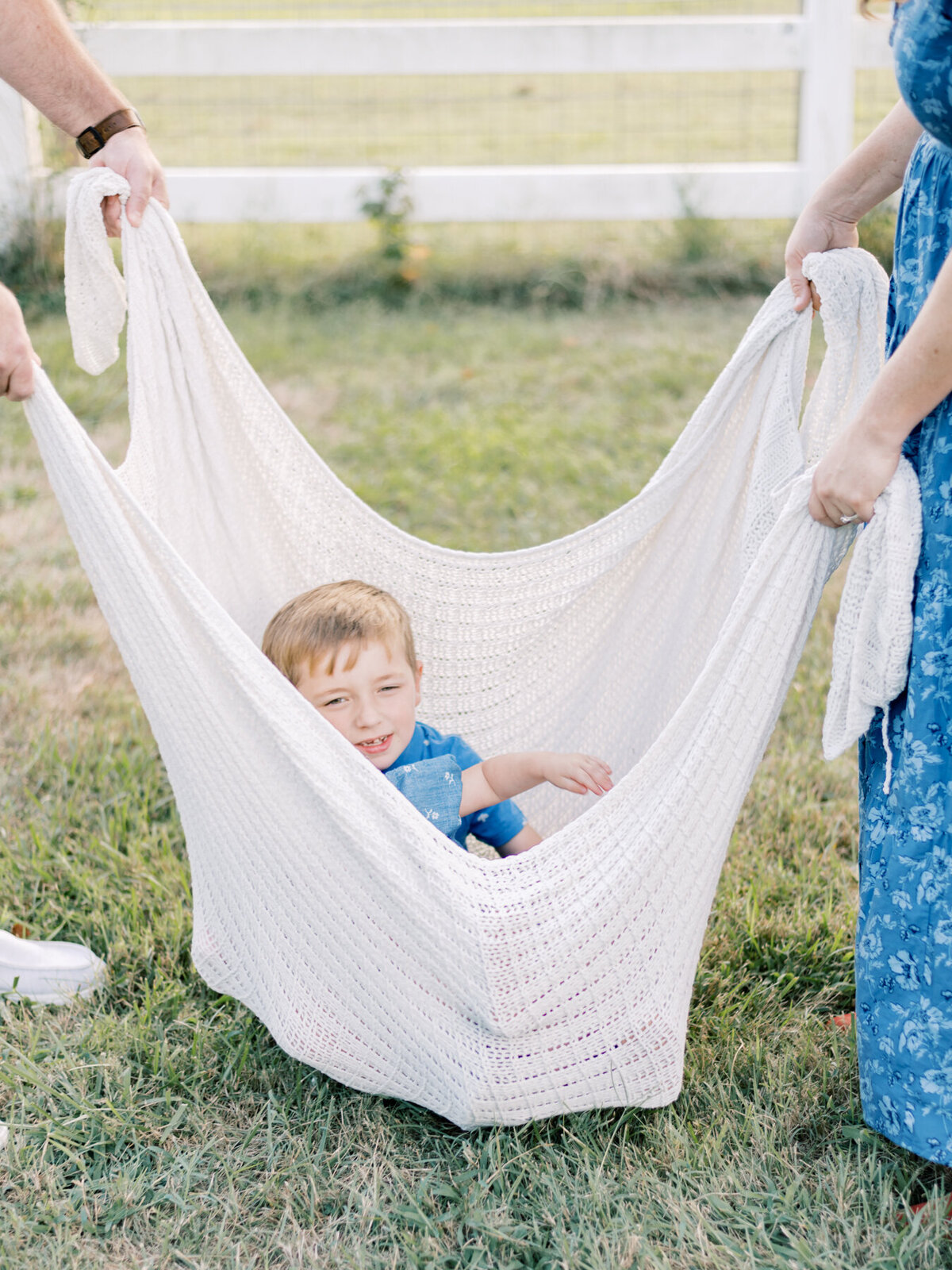 Little boy sitting in blanket as a swing.