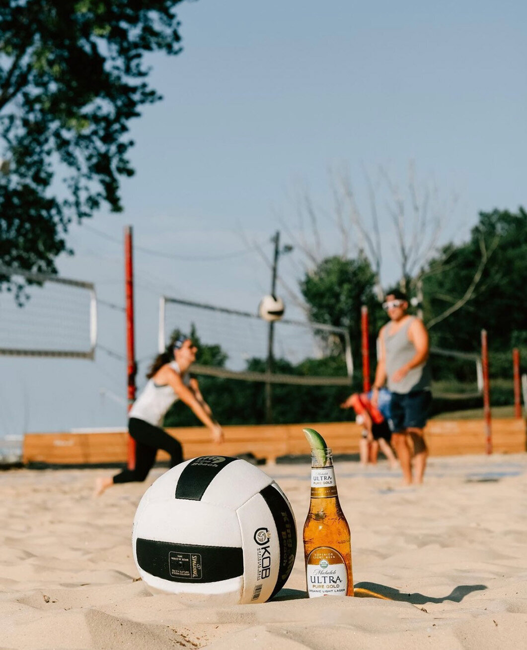 A volleyball and a Michelob beer sit on the sandy beach, perfect for a sunny day of fun and relaxation.
