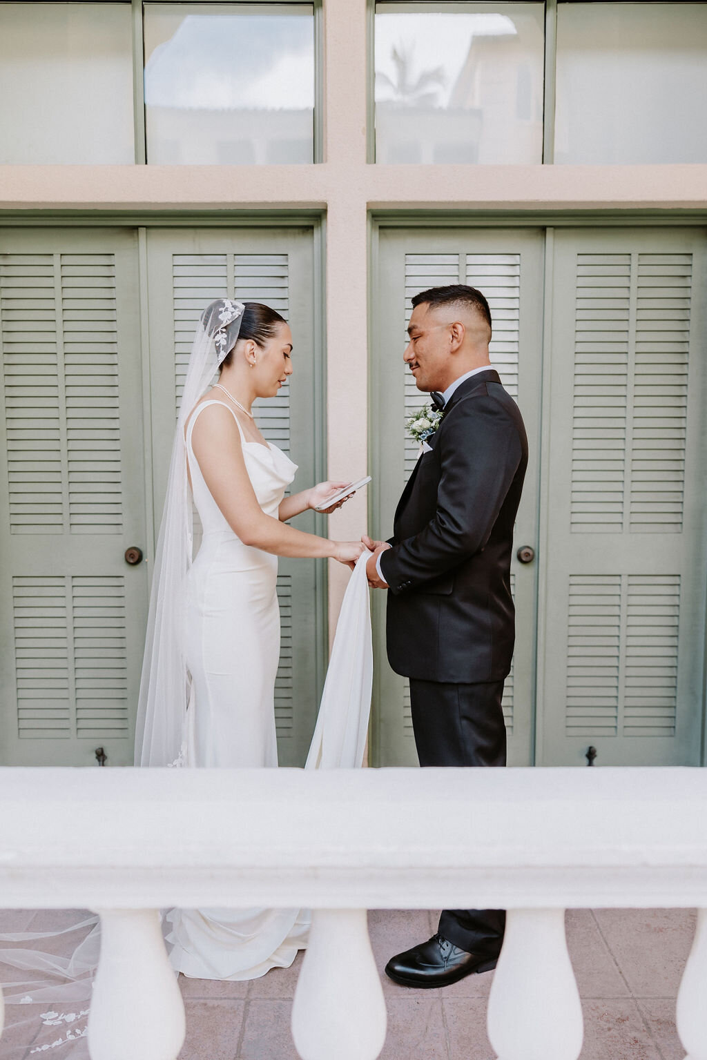 bride and groom facing each other under arches by the pool at cafe julia hawaii
