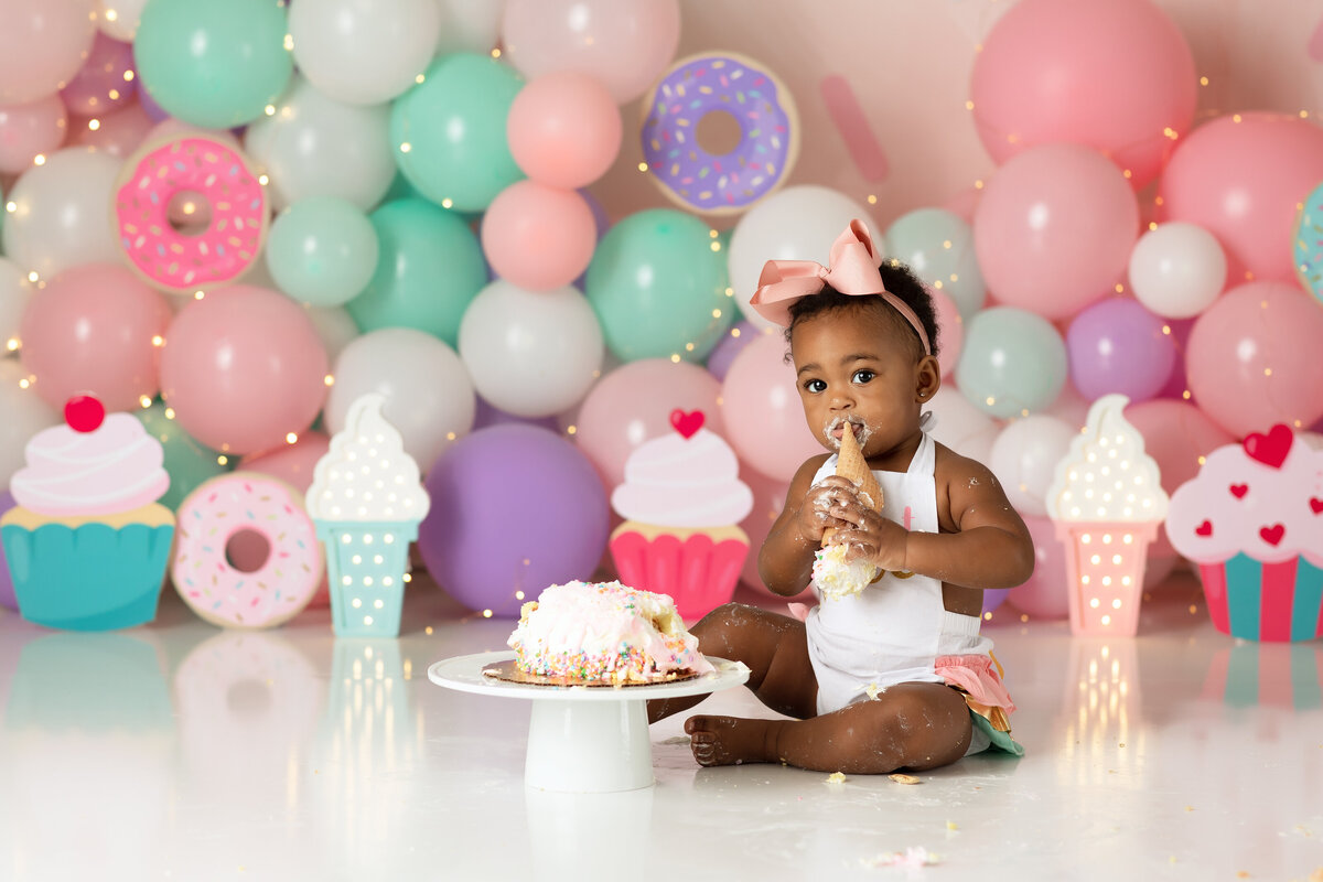 One year old Tampa baby enjoying a personalized luxury cake smash session with sweet one decorations