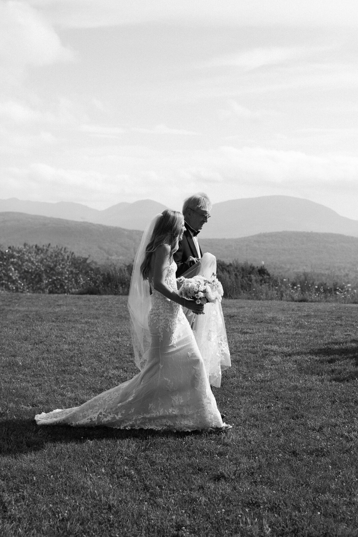 Bride and groom walk in the grass of a Hudson Valley hilltop