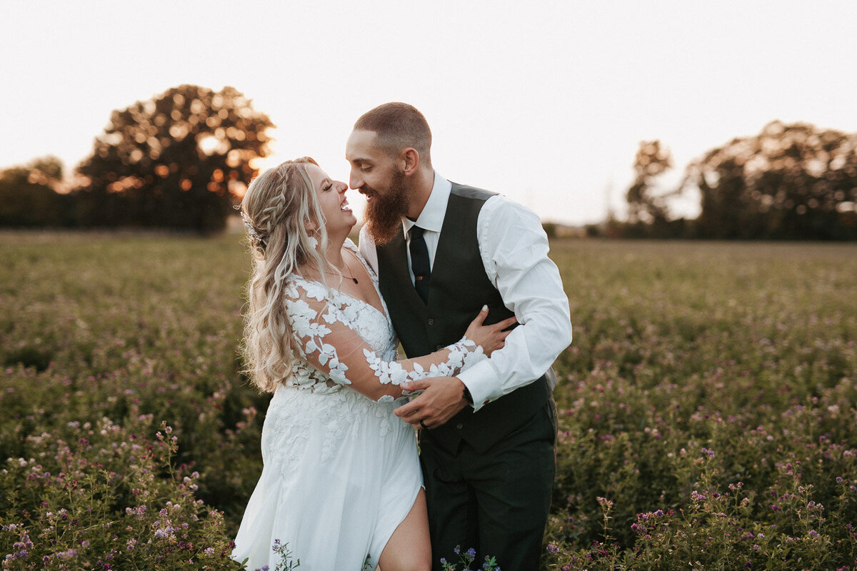 Bride and groom candid moment in open field 