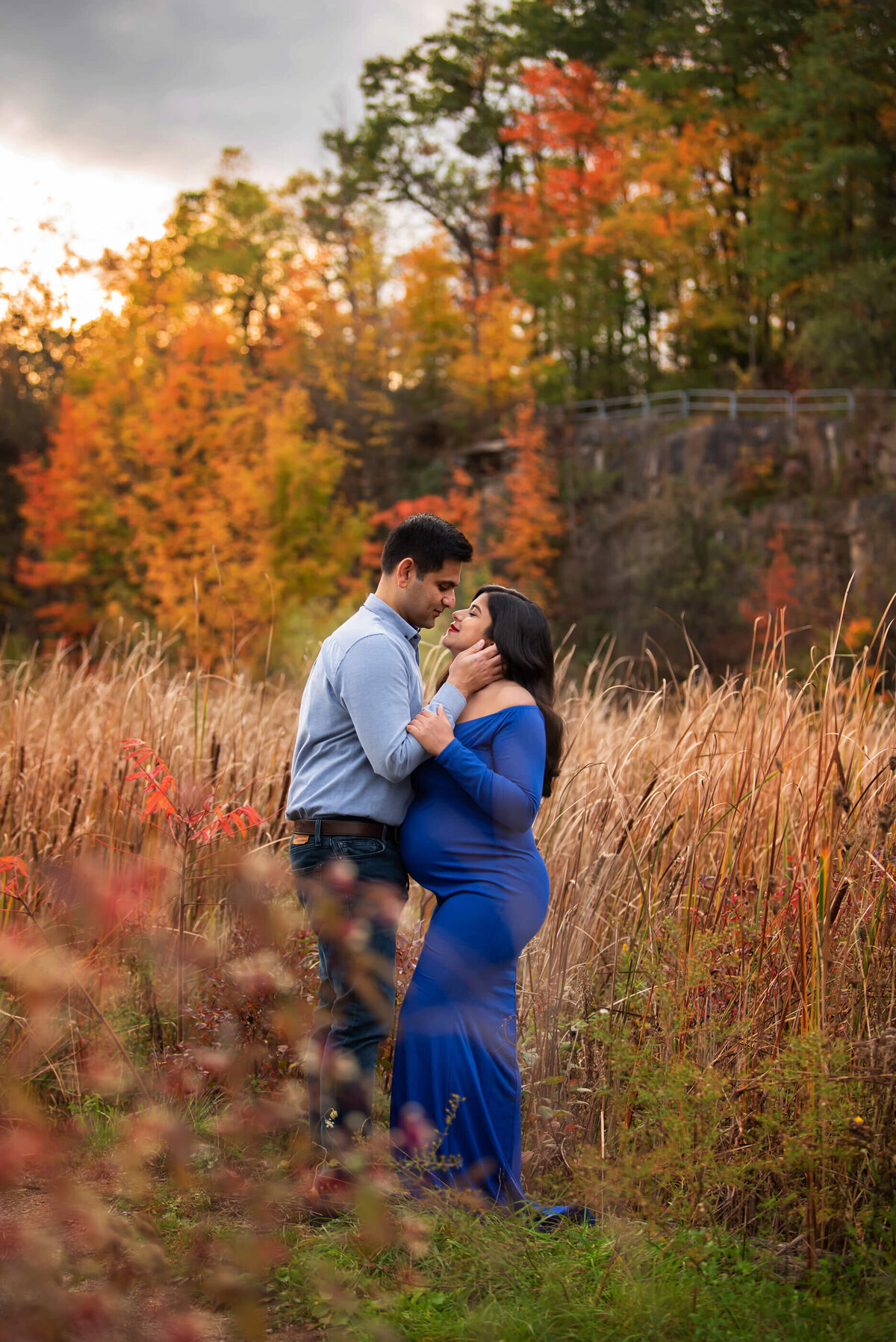 husband and wife embracing for their fall maternity photography session