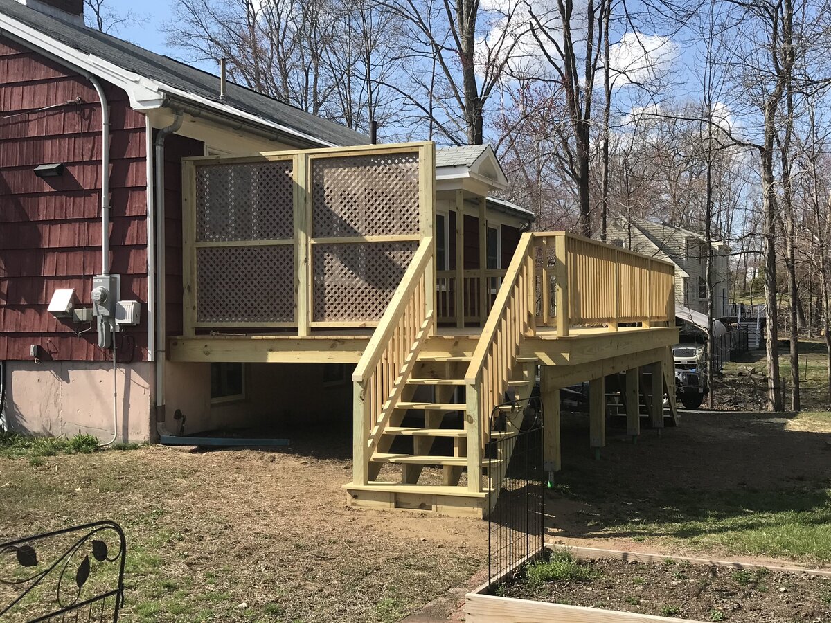 A PT wood deck complete with trellis privacy fence on a red house