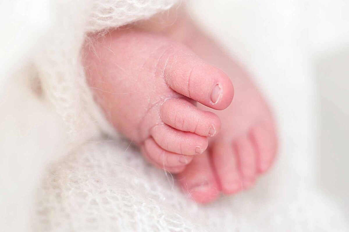 Een prachtige close-up van de kleine voetjes van je baby, vastgelegd tijdens een newborn fotoshoot aan huis.