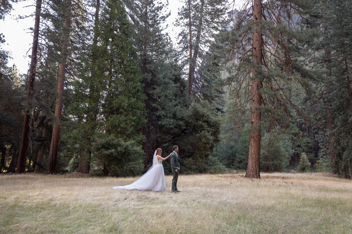 A bride walks up to a groom and taps him on his shoulder for their first look on their elopement day.