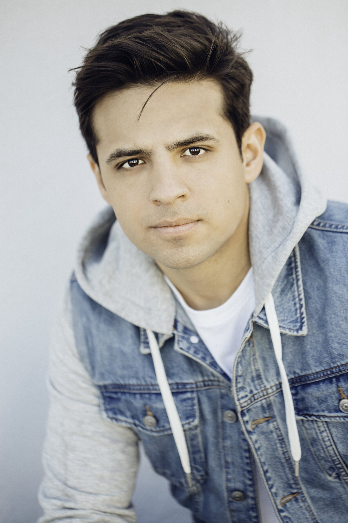 Headshot Photograph Of Young Man In Outer Denim Hoodie And Inner White Shirt Los Angeles