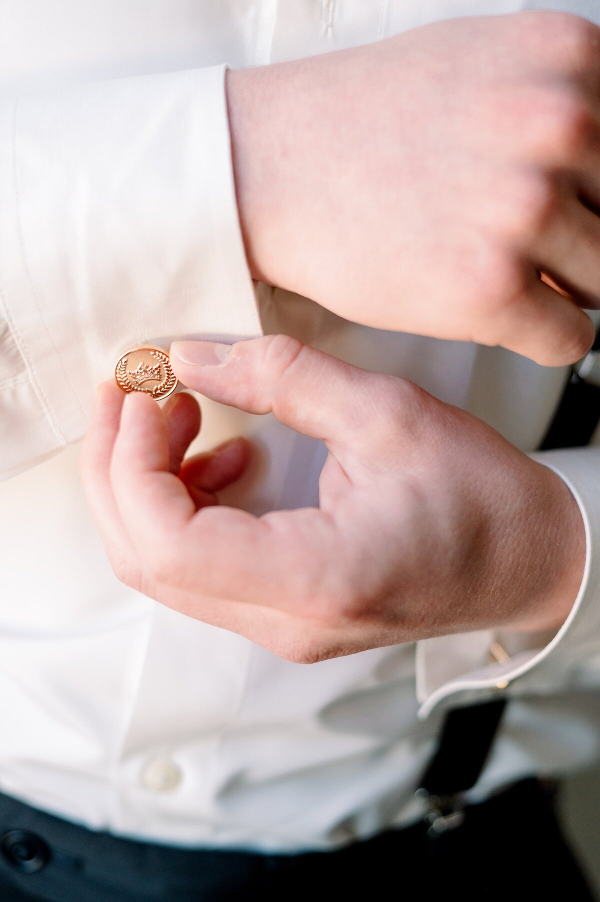 a groom buttoning his cuff links on his wedding day