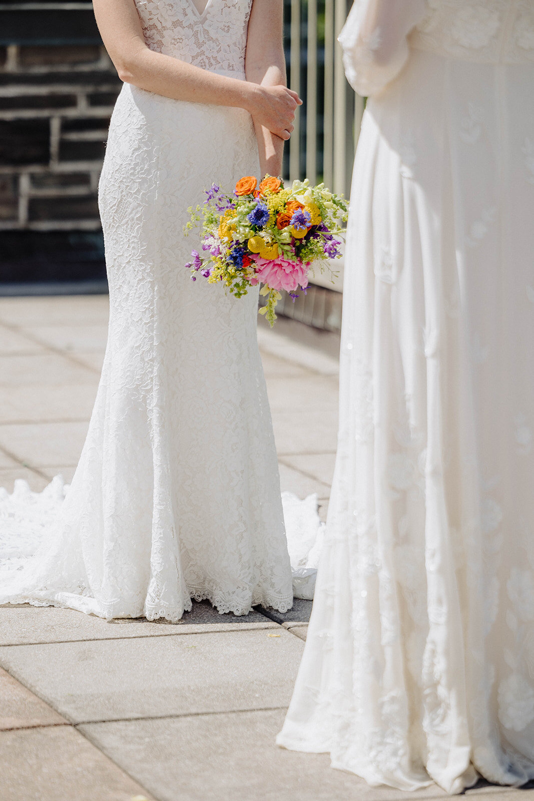 Brides looking at each other holding colorful bouquet