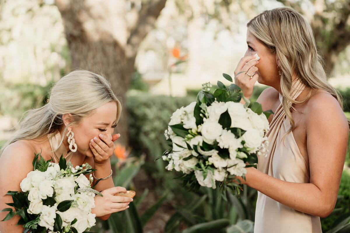 two bridesmaids wearing champagne bridesmaid dresses holding all white bouquets laugh so hard they cry at spanish hills country club wedding captured by los angeles wedding photographer magnolia west photography