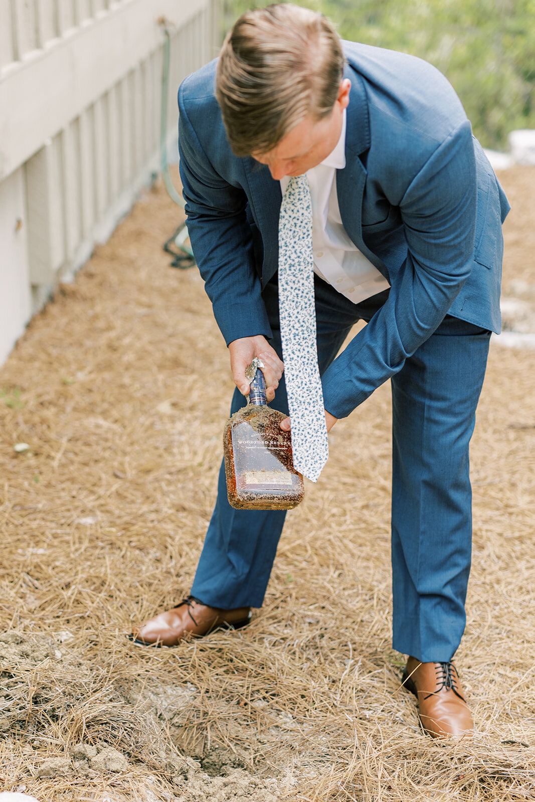 Groom digs up a bourbon bottle as part of the Southern wedding good-weather tradition at a mountain rental home in Cashiers NC.
