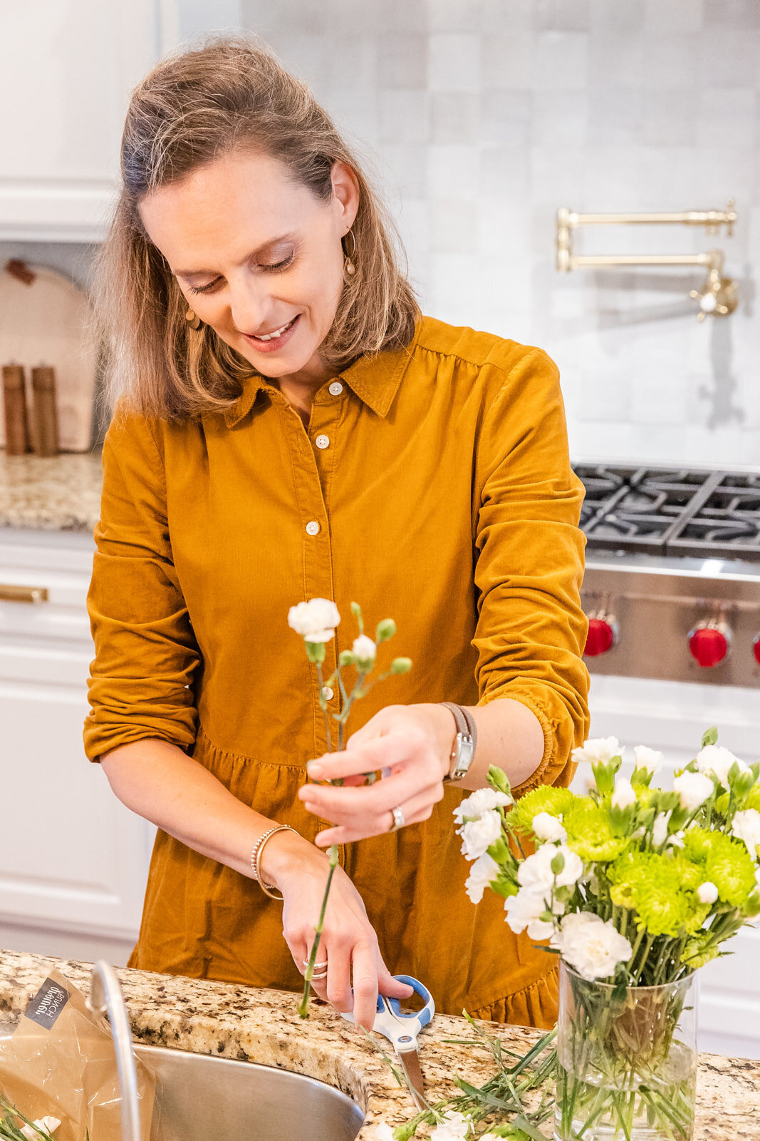 interior designer wearing brown dress  preparing a flower bouquet for a branding photo session in a kitchen Atlanta personal brand photographer | Laure Photography branding