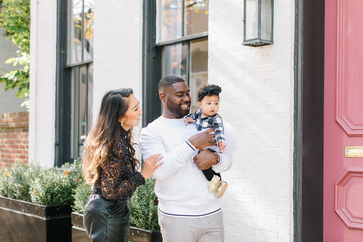 husband and wife with baby in old town alexandria having photos taken