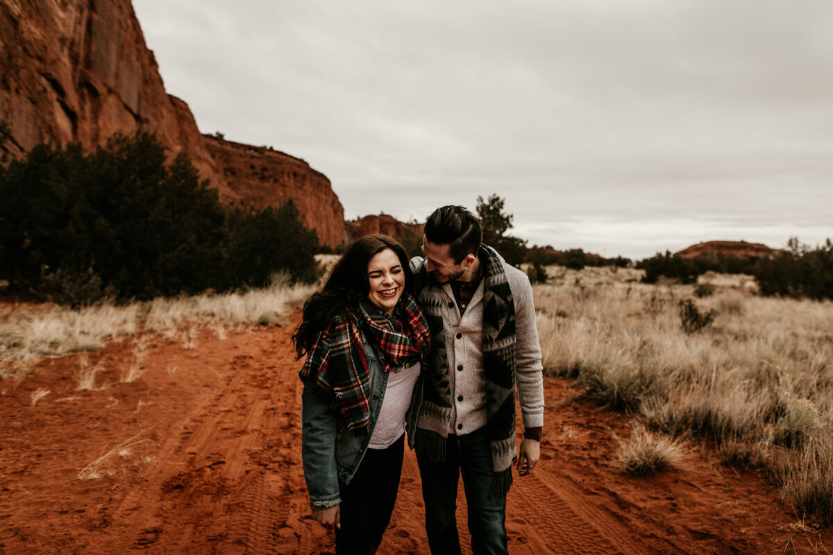 engaged couple holding each other and walking in desert