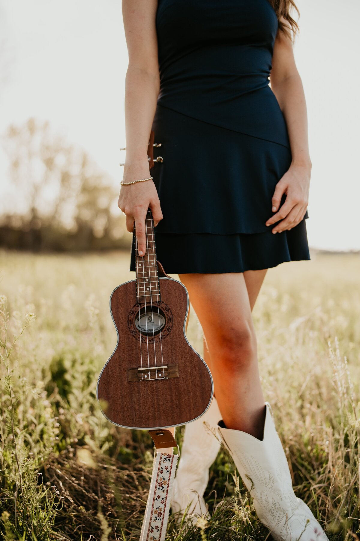 senior standing with ukulele in field, senior photography in amarillo