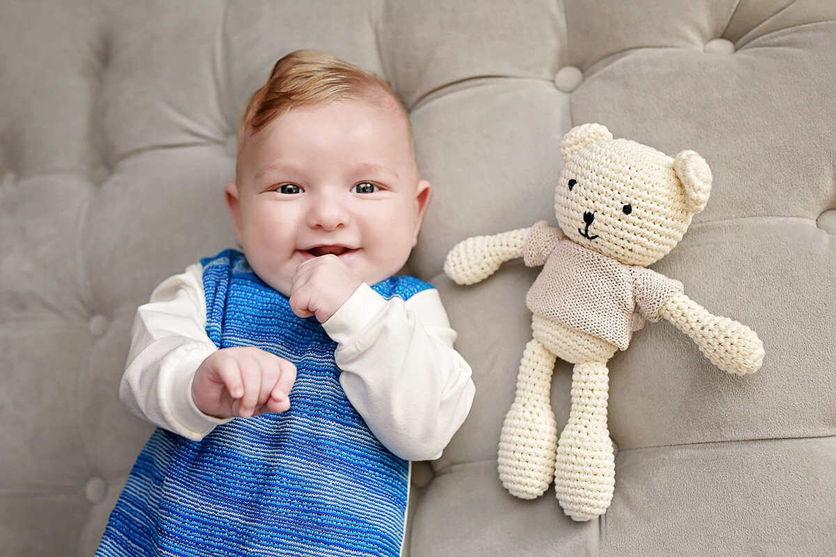 Newborn baby laying down next to knitted bear toy at home in Calgary Alberta photo session
