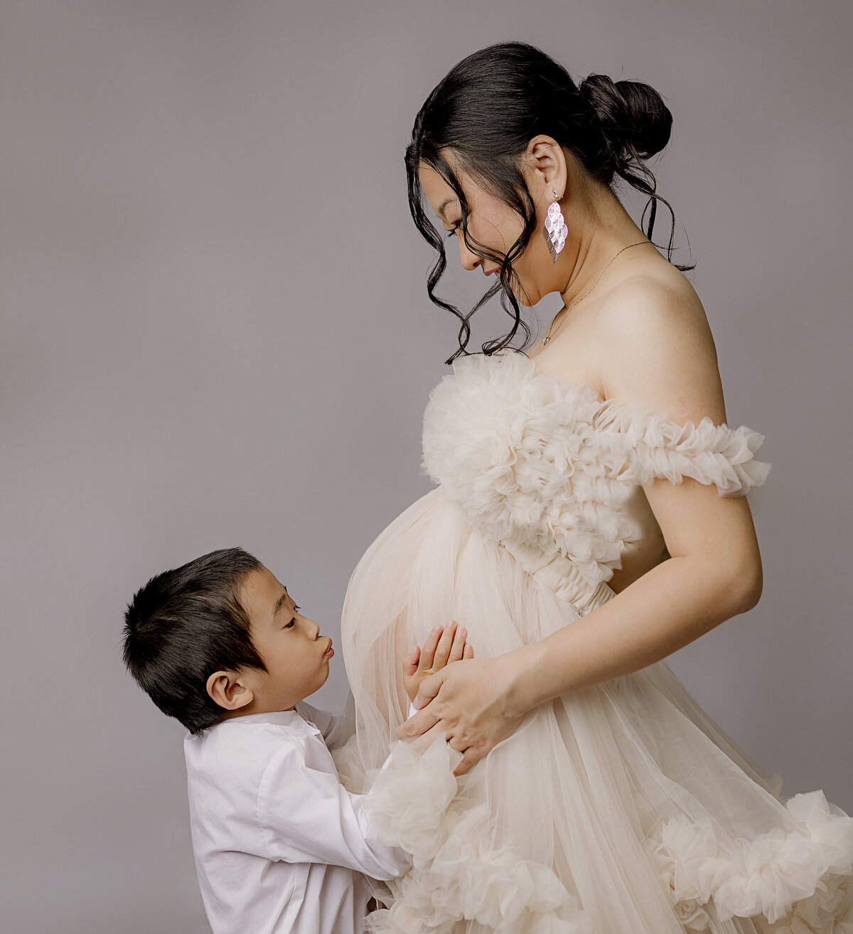 young boy kissing mom's pregnant belly