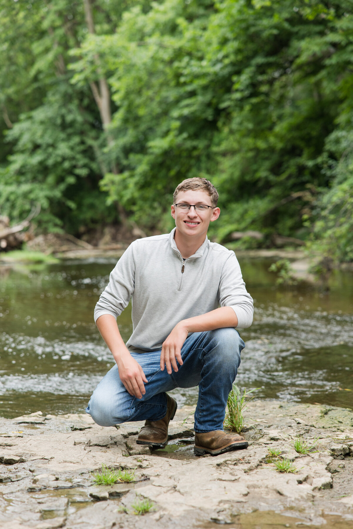 Senior guy in the woods near a creek smiling at the camera
