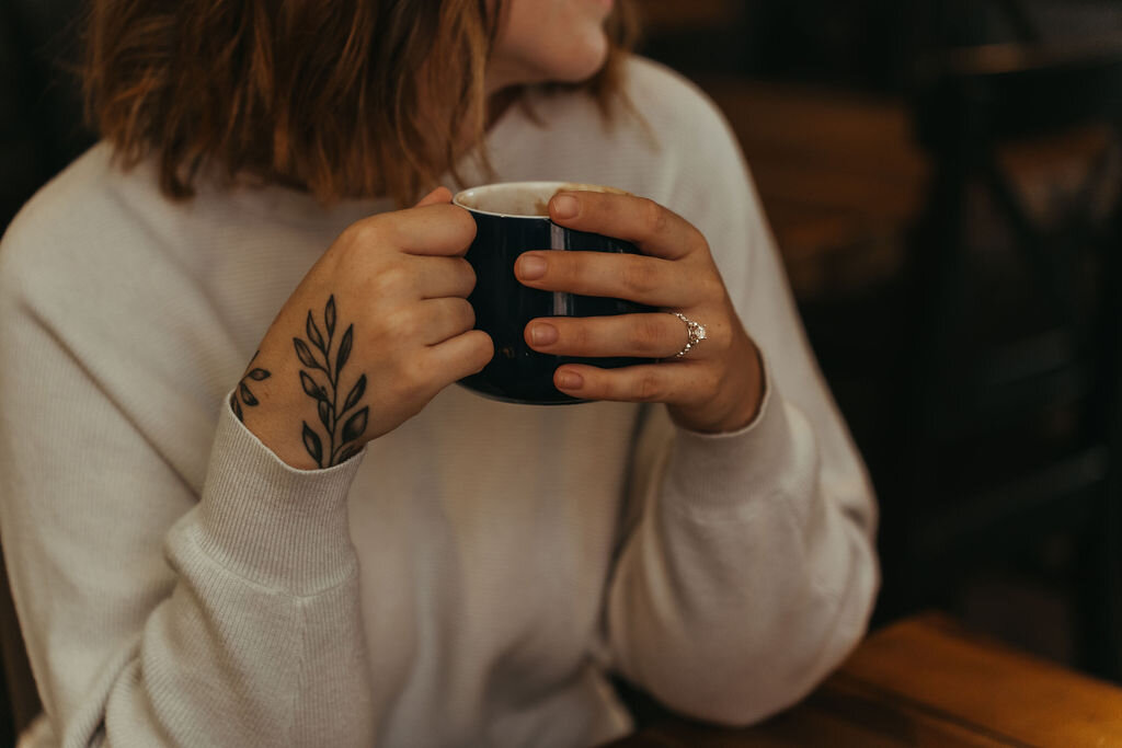 Photo of woman holding coffee mug, with focus on engagement ring