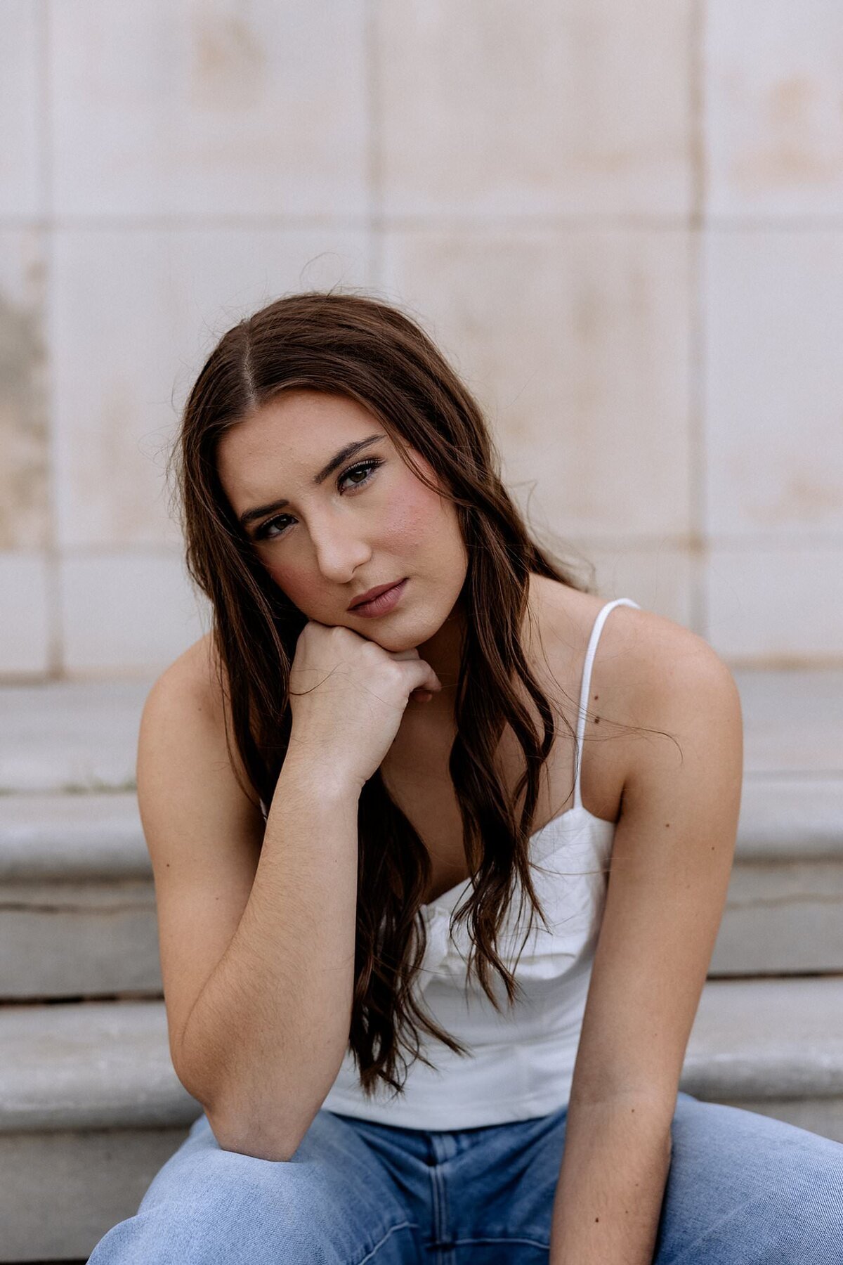 Senior session with senior dressed in a white shirt, she is leaning on her hand.