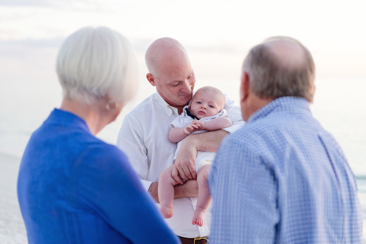 Grandparents look at their grandchild that their son is holding Fort Myers Florida