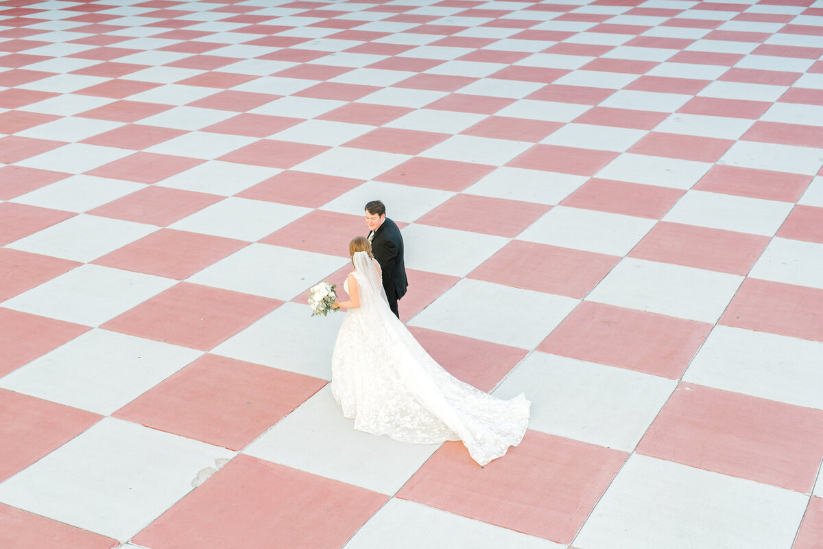 couple walks across checkered floor at Citadel after wedding
