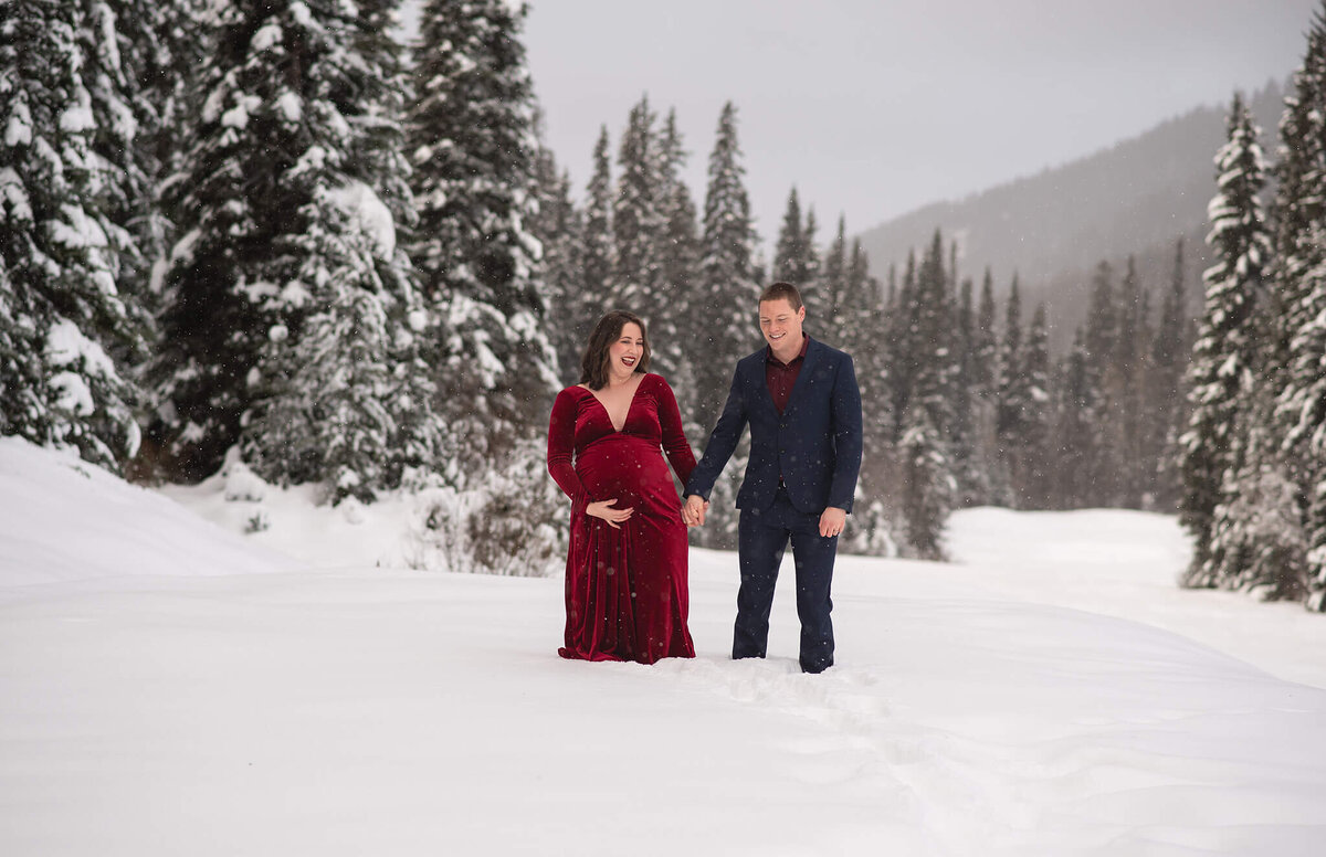 Brittany Danielle is in Sun peaks to capture this winter portrait of a pregnant woman and husband standing hand in hand in the snow.