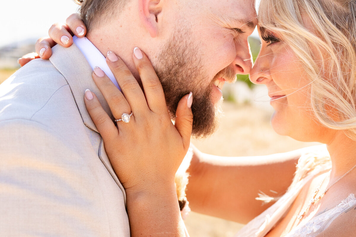 A close-up of the bride and groom leaning in, showcasing the bride’s engagement ring and elegant manicured nails.