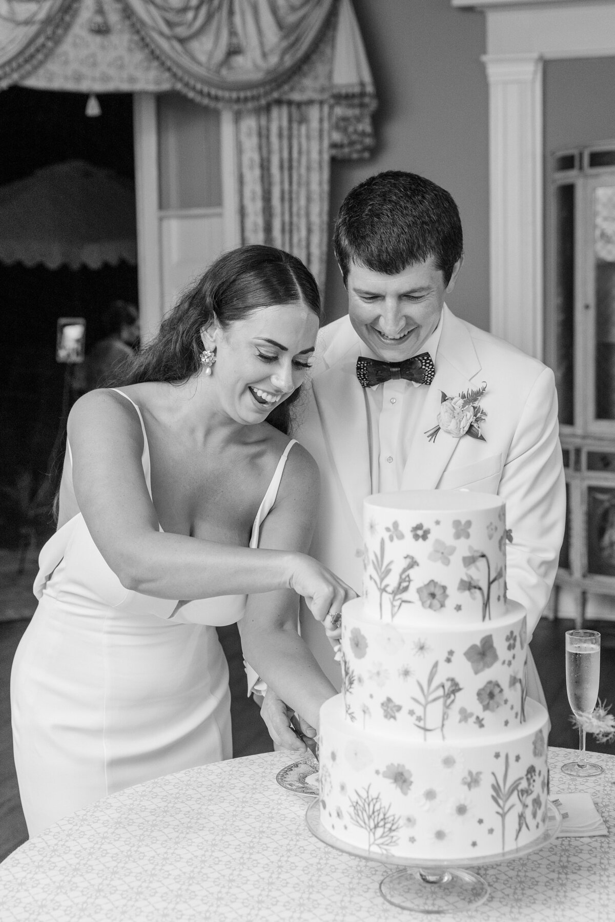 black and white photo of bride + groom cutting their cake
