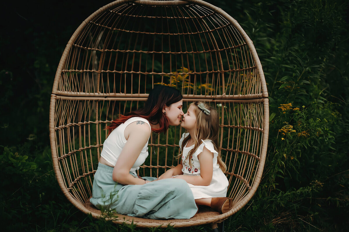 mother and daughter eskimo kissing on a chair