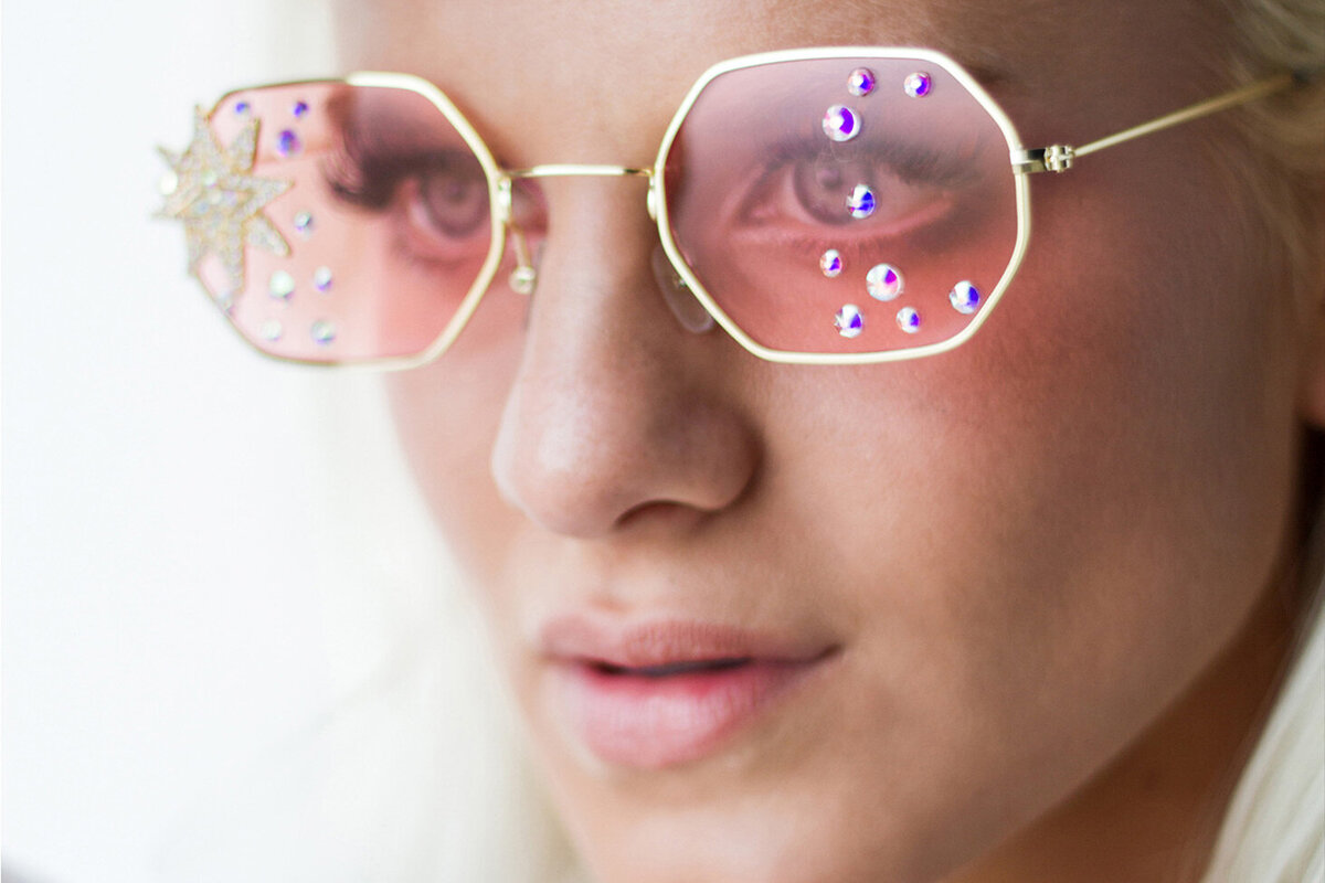 Musician portrait Haley Vassar closeup wearing pink studded sunglasses against white
