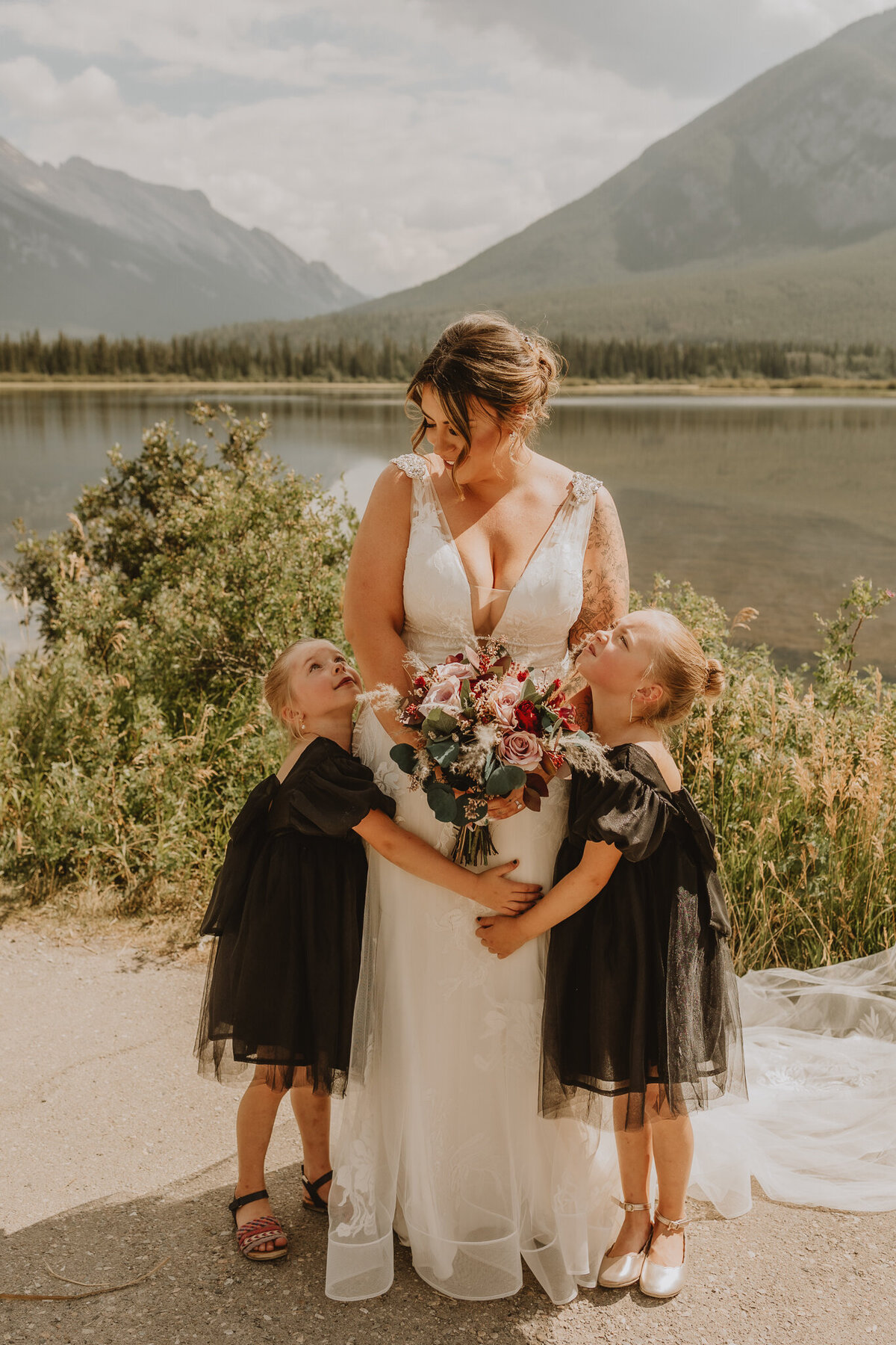 Bride sharing hugs with flower girls in Banff,AB