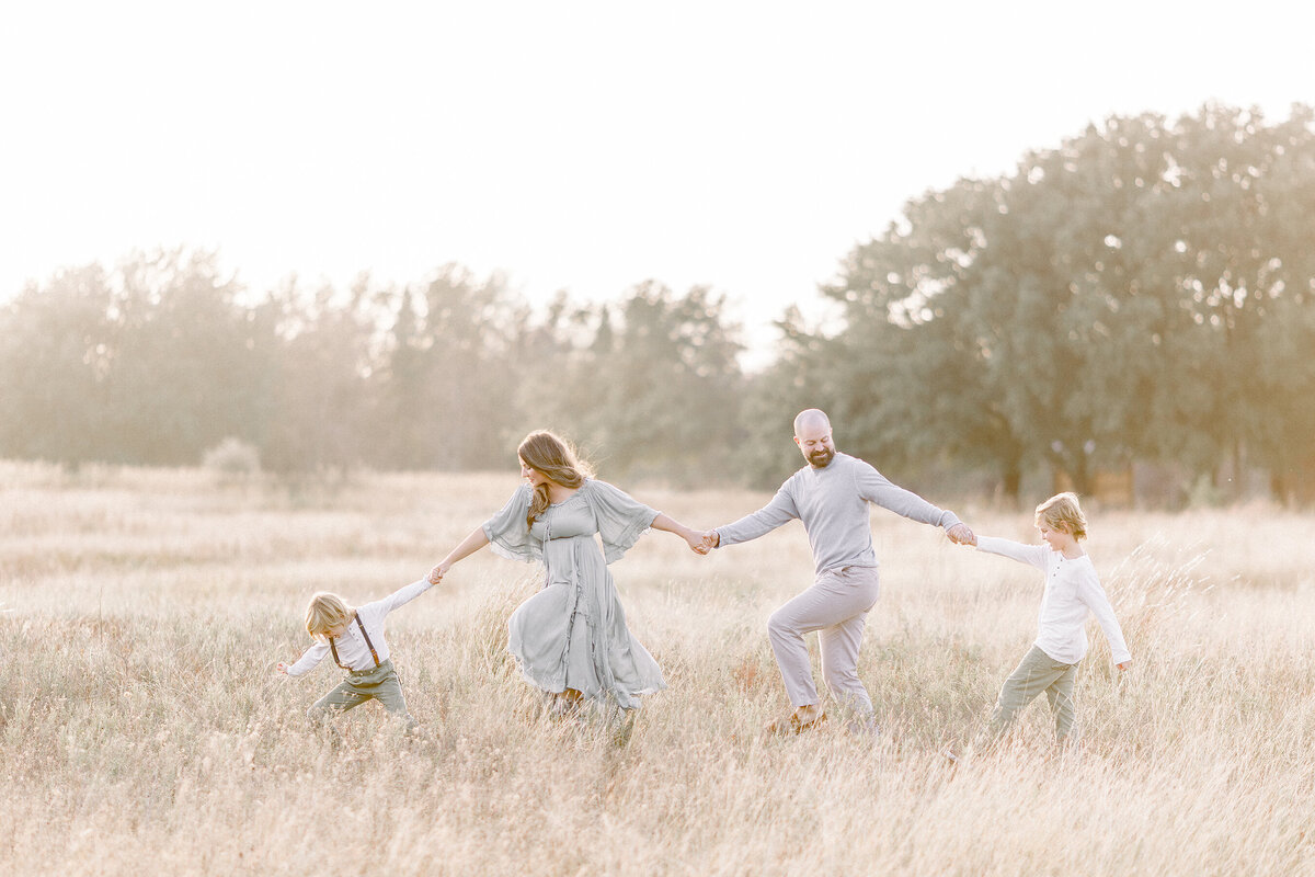 A Frisco Tx Family walking hand in hand though the middle of a field for family photos.
