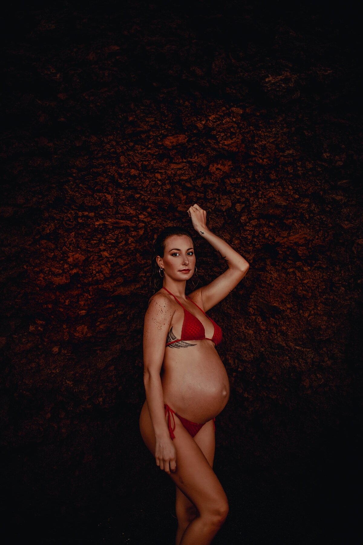 Black sand beach portraits of pregnant woman wearing sexy red bikinis on Maui