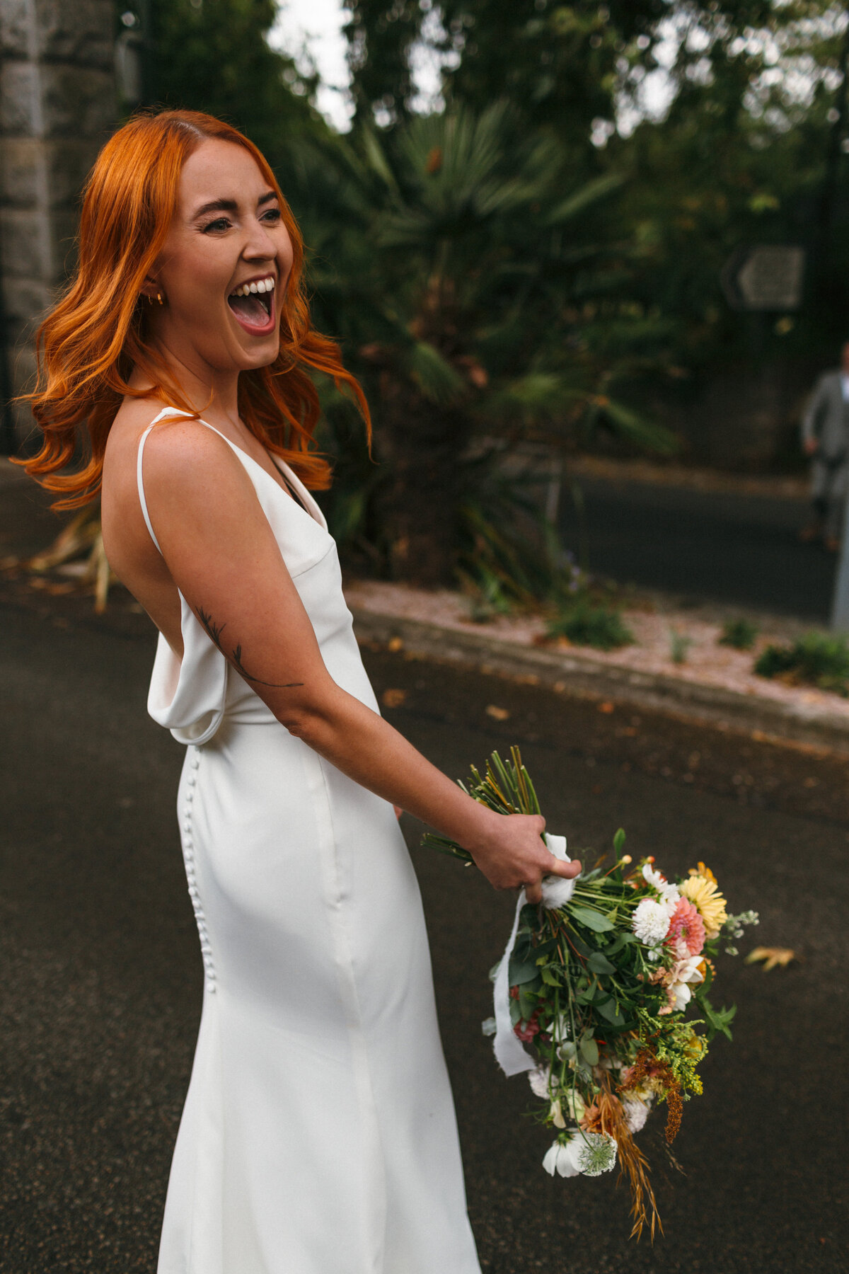Red haired bride laughs before crossing the road
