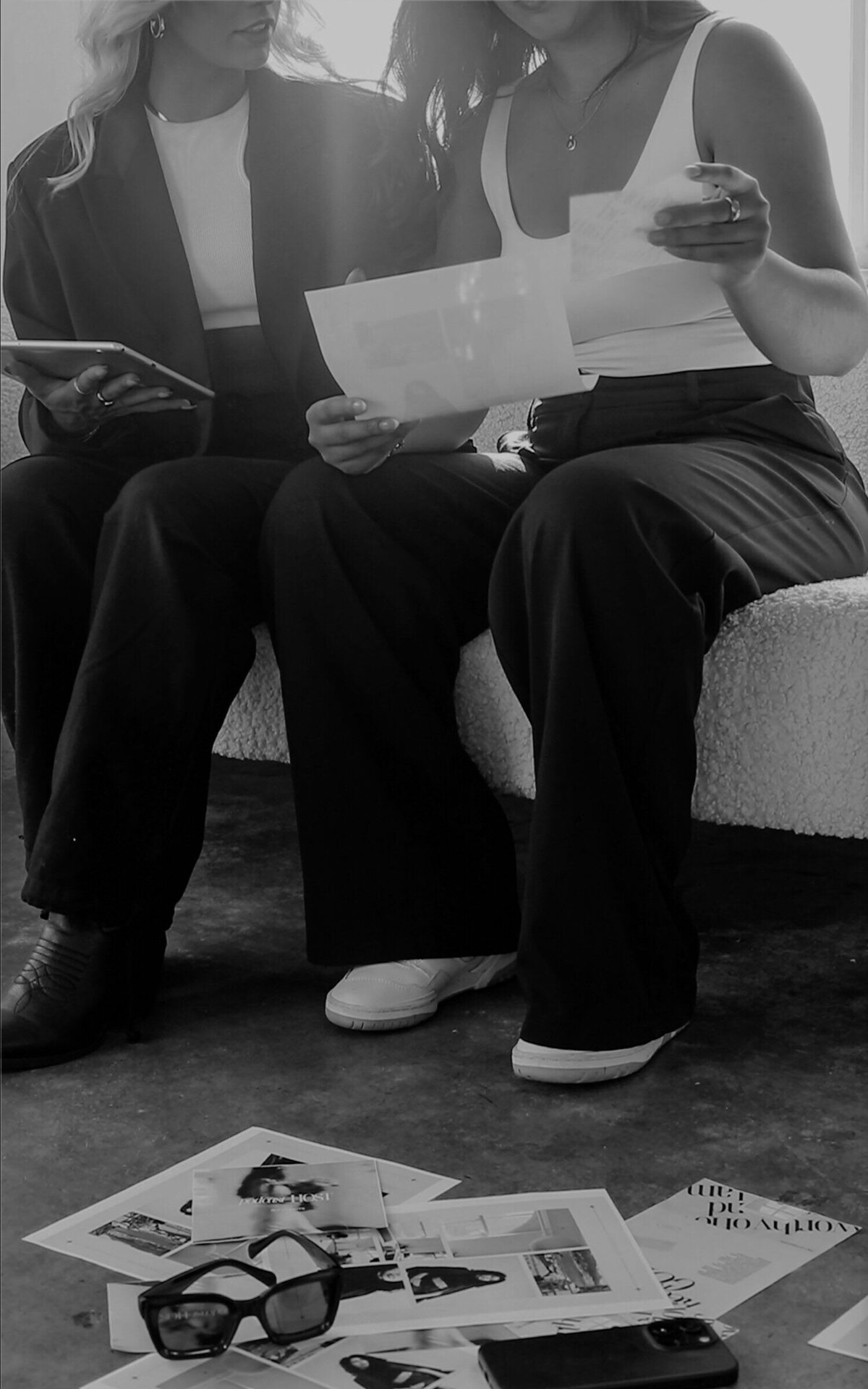 Two women collaborating with digital tablet and paper notes, representing strategic and stylish web design services by Aurum Design Studio