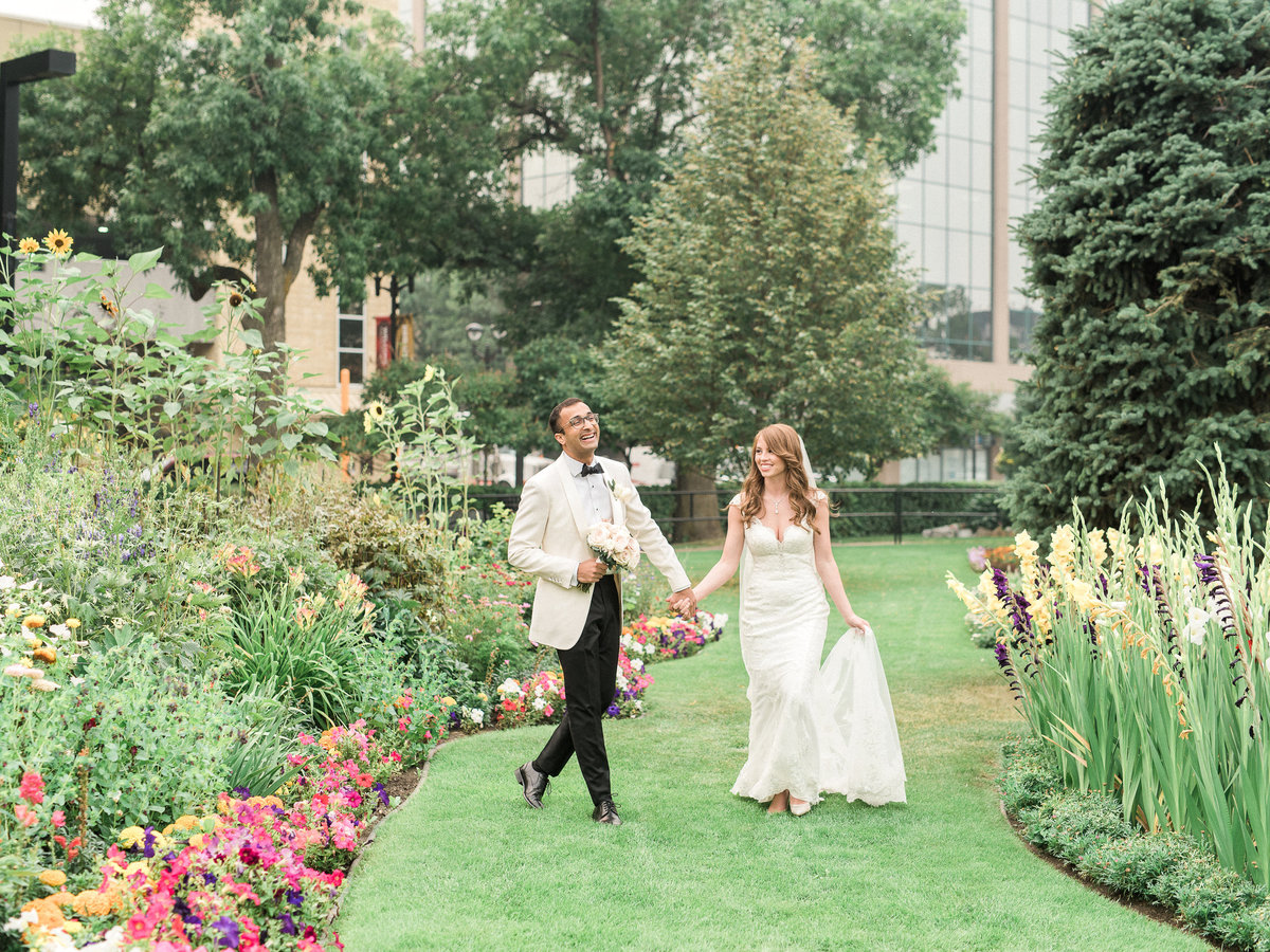 Wedding day couple holding hands running through green field