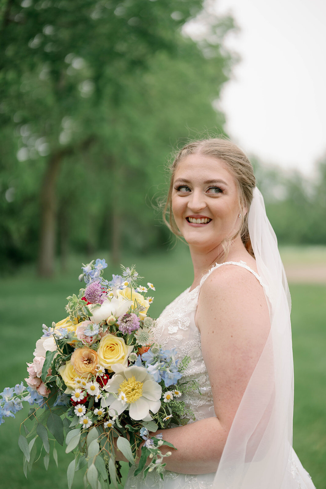 Joyful solo portrait of the bride laughing over her shoulder during her wedding day at The Blue Heron Barn in Kalamazoo MI.