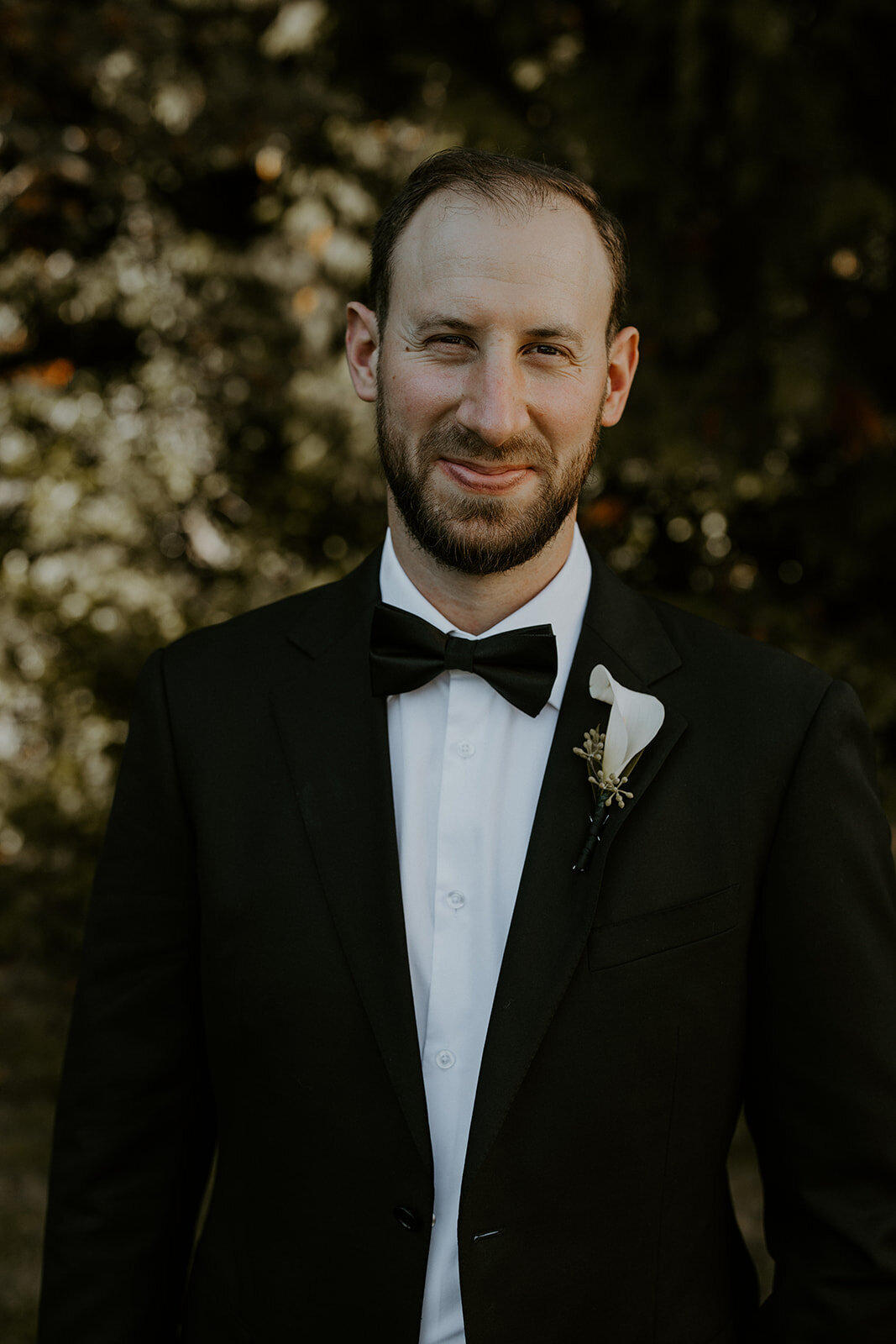 Groom wearing black suit with a flower on wedding day
