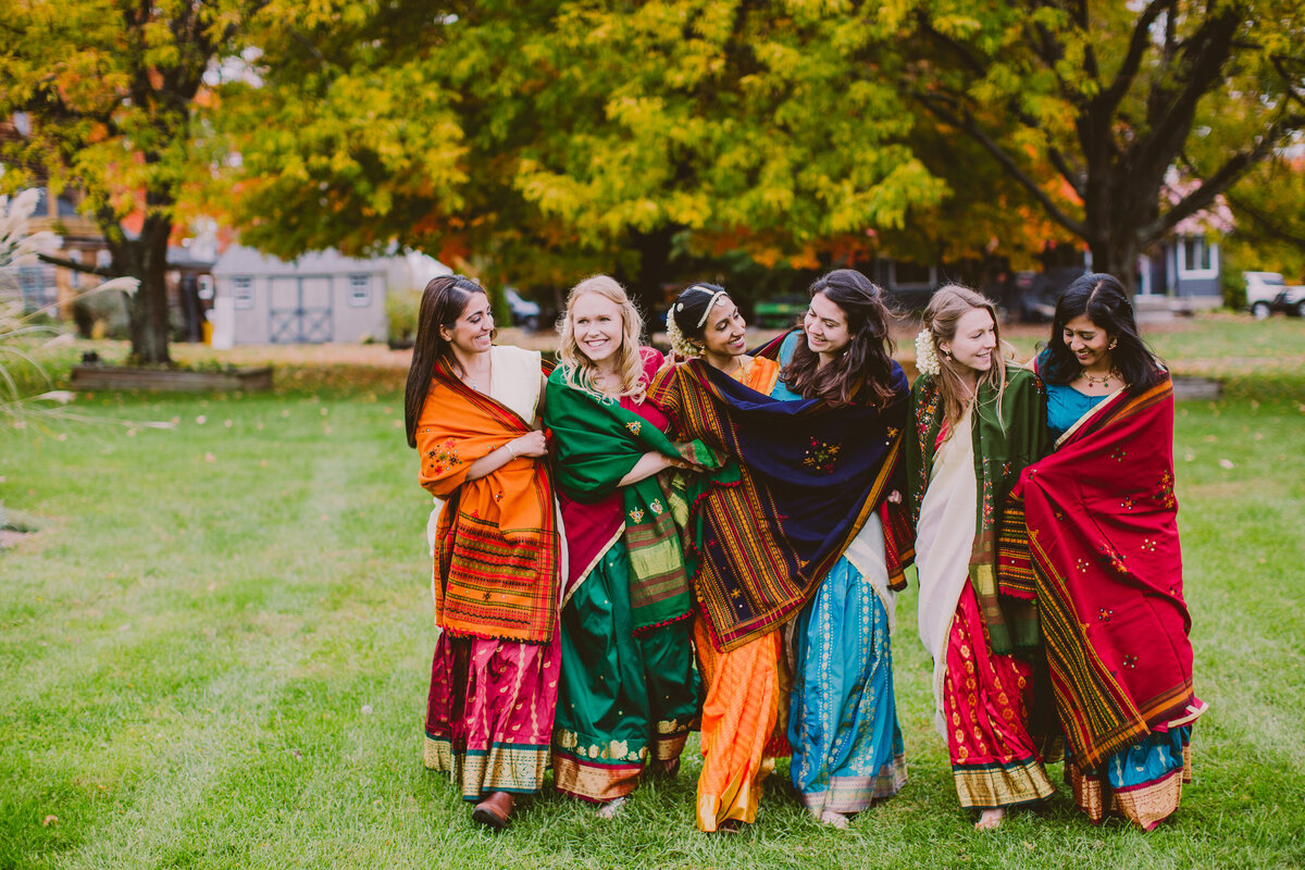 south indian bride walking with her bridesmaids covered in colorful shawls at red maple vineyards in the fall