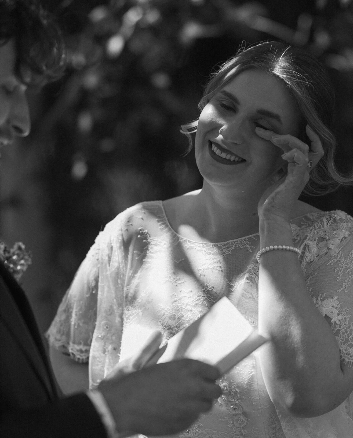 bride wipes away a tear as the groom reads his vows during a private elopement session in Bend, OR on a sunny day